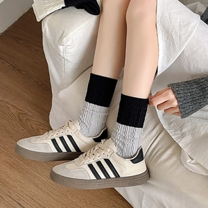 Retro cream sneakers with black stripes and gray knit crew socks in casual home setting