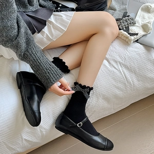 Detail of ruffle cuff socks with a polka dot bow and black Mary Jane shoes