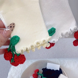 Détail de chaussettes en tricot avec cerises 3D faites main et bords volantés