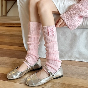 Détail de la maille rose des jambières avec de petits nœuds en ruban de satin