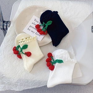 Détail des bords à volants sur chaussettes en coton avec décor de cerises tricotées