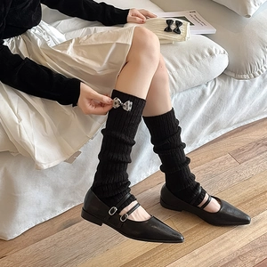 Détail de jambières noires tricotées avec nœuds à pois et chaussures Mary Jane