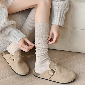 Detailed view of beige ribbed calf socks paired with vintage khaki suede mule clogs