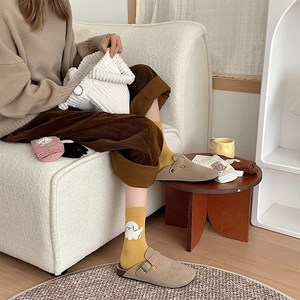Détail de chaussettes en tricot jaune à motif caniche blanc et chaussons marron chauds
