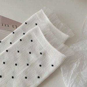 Detail of white cotton crew socks with black polka dots and delicate lace trim cuff