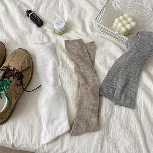 Detailed texture of white, beige, and grey Japanese style ribbed calf socks on a bed