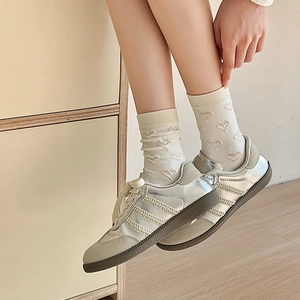 Detail of cream crew socks with embossed heart patterns paired with silver metallic sneakers