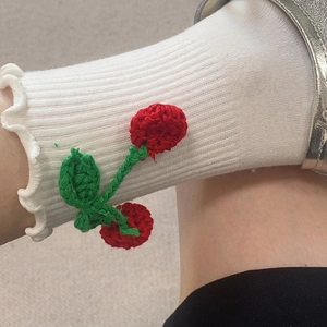 Détail de chaussettes blanches en coton avec cerises 3D tricotées et bords à volants