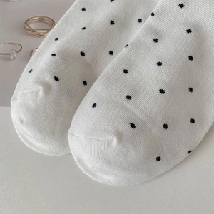 Close-up of white knit socks with black polka dots and vertical rib texture details