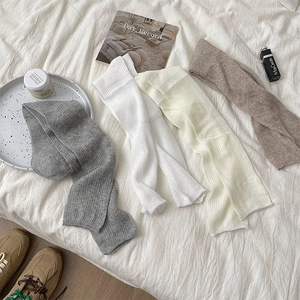 Detail of knit knee-high socks featuring vertical ribbed textures in neutral tones