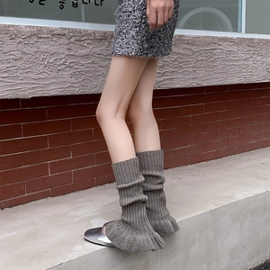 Close-up of dark grey knitted leg warmers with vertical ribs and ruffled hem detail