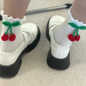 Détail de chaussettes blanches à volants avec cerises crochetées et chaussures Mary Jane