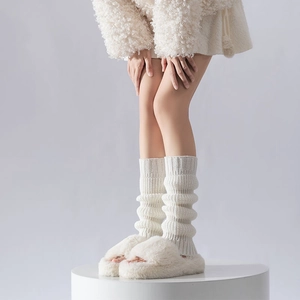 Detail of chunky cable knit leg warmers paired with plush faux fur slippers