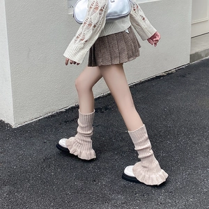 Detail of beige knit leg warmers with vertical ribs and sweet ruffled flared cuffs