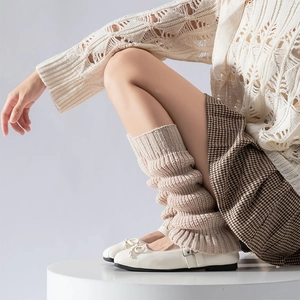 Close-up of beige cable knit leg warmers paired with houndstooth skirt and Mary Jane shoes
