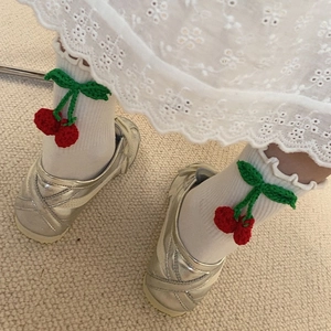 Détail de chaussettes en coton blanc avec cerise au crochet 3D et bords à volants