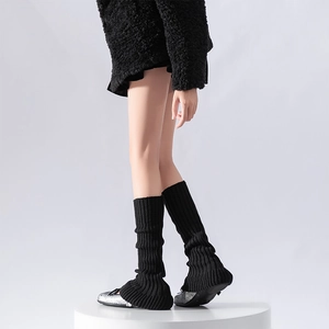 Detail of black knit leg warmers with vertical rib texture and ballet style aesthetics