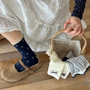 Detail of floral socks with navy patterns, ruffle trim, and bows in Mary Jane shoes