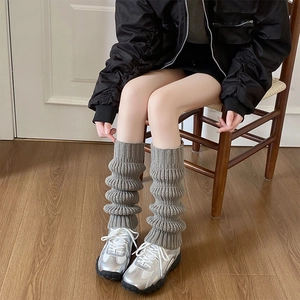 Detail of thick knit texture on grey leg warmers with stylish pleated layering effect