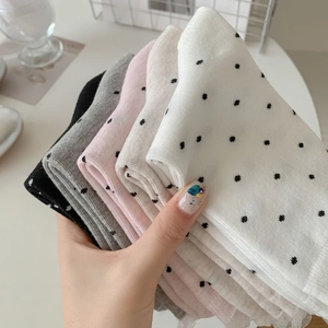 Close-up of knit socks with polka dots and delicate lace trim in various soft colors