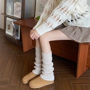 Detail of chunky knit leg warmers paired with chestnut suede mules in cozy winter style