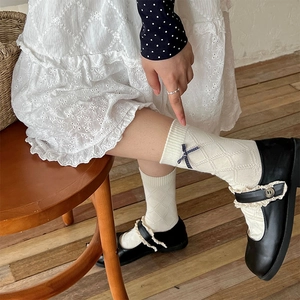 Detail of ivory mid-calf socks with diamond lattice texture and side bow accent
