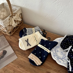 Three-pack of vintage floral crew socks with ruffles and bows in a cozy home setting
