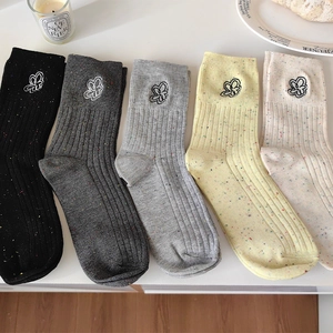 Dettaglio del ricamo floreale su calze a coste con trama in maglia colorata a pois