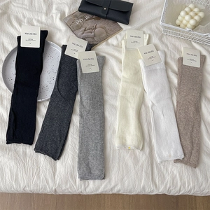 Detailed knit texture of six cotton calf socks in neutral colors on a cozy fabric
