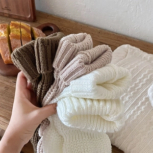 Detailed close-up of thick ribbed knit leg warmers in various neutral winter tones