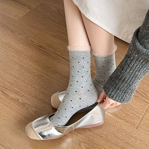 Detail of grey polka dot knit socks with delicate pink lace trim styled with silver shoes