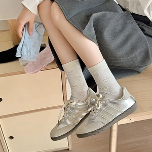 Women's crew socks with heart jacquard pattern paired with silver sneakers shoes