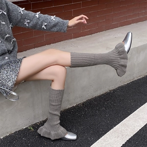 Detail of grey rib-knit leg warmers with ruffle edge over silver square-toe shoes