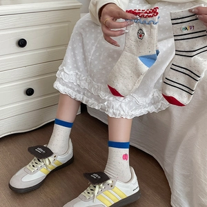 Detail of knit socks showing cartoon bear embroidery and striped pattern with colorful dots