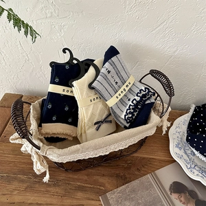 Three pairs of vintage floral and ribbed crew socks with bows in a rustic gift basket