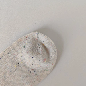 Dettaglio ravvicinato di calze in maglia con trama a puntini colorati e cucitura fine in punta