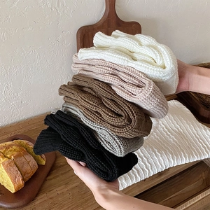 Detailed knit texture of thick leg warmers in white, beige, brown, grey and black