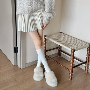 Detailed view of cream plush slippers with thick soles and soft faux fur texture