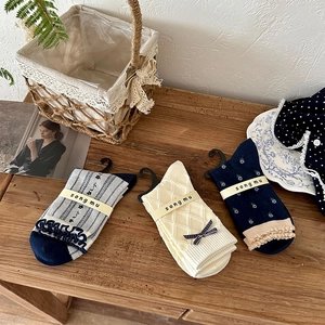 Detailed close-up of vintage floral crew socks with ruffles and bow tie on wood surface