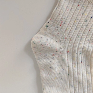Dettaglio ravvicinato di calze a costine color panna con filato maculato e trama morbida