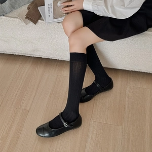 Detailed view of black knee-high socks with vertical knit texture and Mary Jane shoes