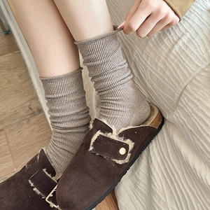 Gros plan de chaussettes en maille grise avec des sabots Boston en daim marron
