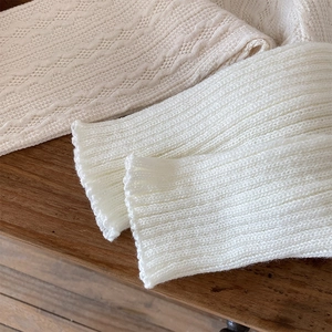 Detailed knit patterns of ivory lace pointelle and white ribbed leg warmer socks