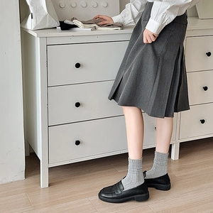 Gros plan de chaussettes en maille côtelée gris foncé avec mocassins noirs de style épuré