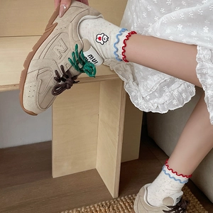 Detailed close-up of ruffle edge socks with cartoon embroidery and retro suede sneakers