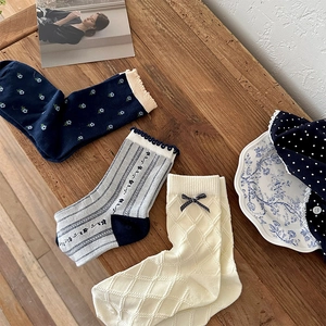 Detailed view of three pairs of vintage floral cotton socks with bows on wood background