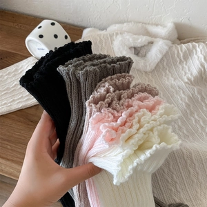 Close-up of knit leg warmers with layered ruffle lace trim in multiple colors
