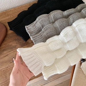 Detailed view of chunky knit leg warmers in black grey and cream white with ribbed edges