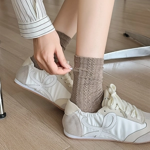 Détail de chaussettes en maille côtelée marron clair avec baskets rétro en patchwork