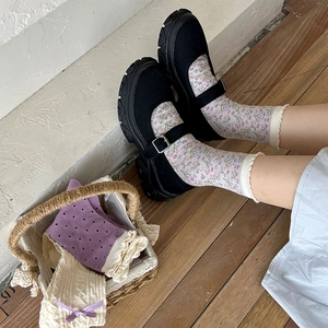 Detail of black Mary Jane platform shoes with purple floral crew socks on wooden floor